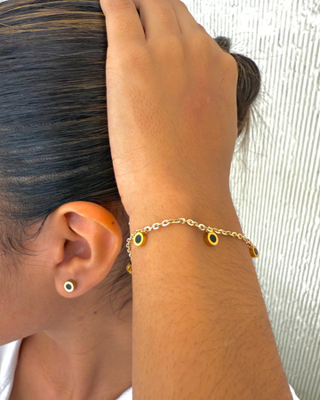Stylish person wearing a Jason Hyde gold-tone bracelet with black and gold charms