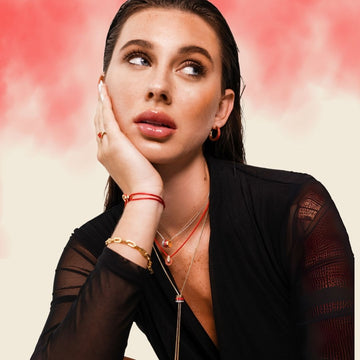 Woman looking up, showcasing Jason Hyde red and gold jewelry.