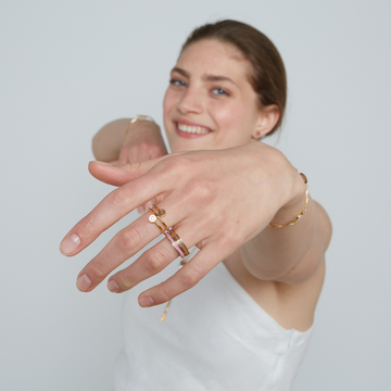 Smiling woman showing gold rings and bracelets with colorful recycled ocean plastic accents