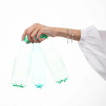 Hand holding water bottles with turquoise and white bracelets