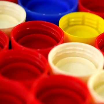 Close-up of a pile of colorful recycled plastic bottle caps in red, yellow, blue, and white