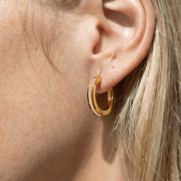 Sleek hoop earring featuring an environmentally beige element.