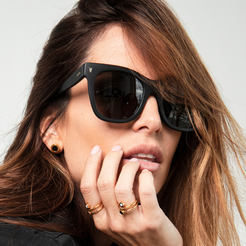 Woman wearing gold rings and stud earrings with black details