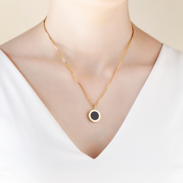 Woman wearing a delicate Jason Hyde necklace with a black sustainable chip pendant.