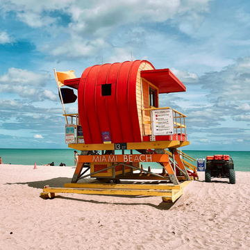 Iconic red and yellow lifeguard stand on the sandy shores of Miami Beach