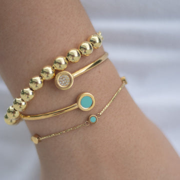 Woman’s wrist adorned with three elegant Jason Hyde gold bracelets