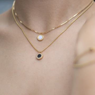 Layered gold necklaces with white and black chips.