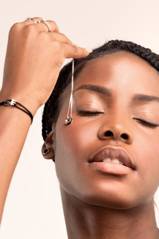 img-banner-Woman holding a bracelet in her hand and letting it fall onto her cheek.