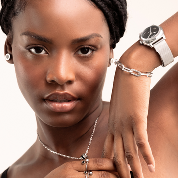Silver-tone watch, link bracelet, chain necklace, and stud earrings on a woman.