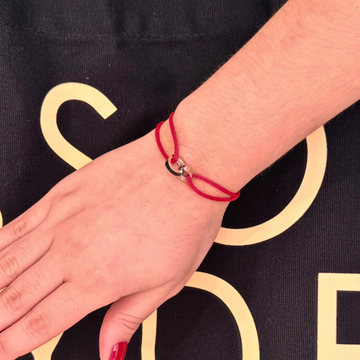 Stylish wrist adorned with a Jason Hyde red cord bracelet.