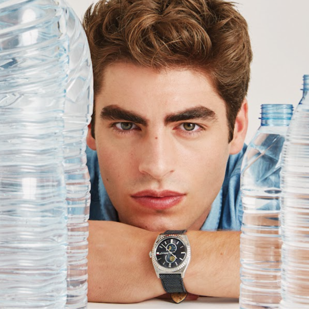 Man modeling a silver watch with a dark dial and black strap.