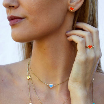 Woman wearing Jason Hyde gold jewelry set with red, blue, and yellow heart details