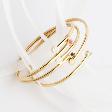 Eco-friendly gold bracelets with colorful circular charms made from ocean plastic