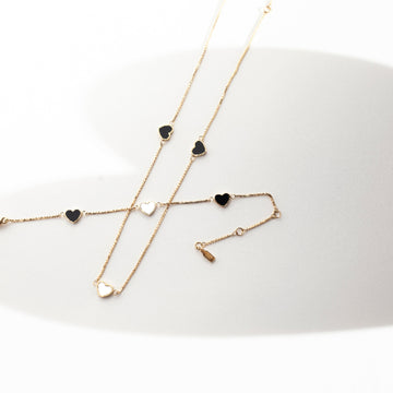 Gold necklace with black and white heart charms
