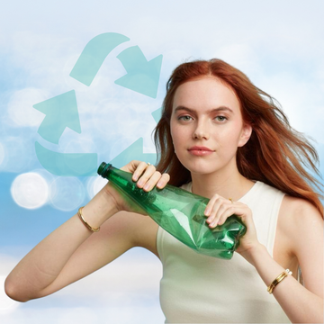 A woman with red hair holding a green plastic bottle, wearing Jason Hyde jewelry
