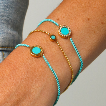 Stack of three bracelets: turquoise cords and gold charms.