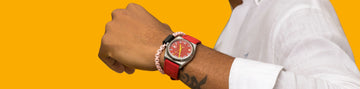 Close-up of a person's arm wearing a red-strapped watch and a light pink chain bracelet