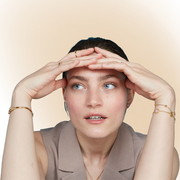 A woman with a natural look and wet hair wearing a Jason Hyde layered set of gold-toned bracelets