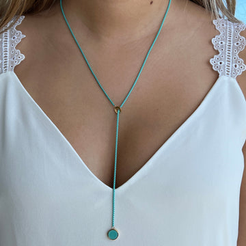Woman wearing a Turquoise lariat necklace with gold accents.