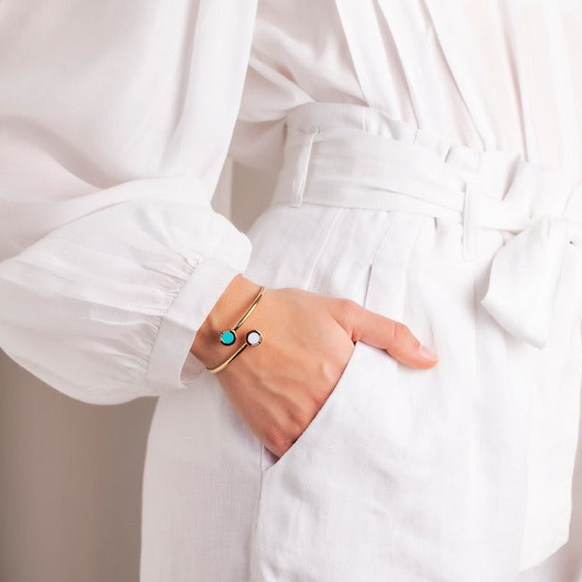 Woman wearing a gold bangle with turquoise and white chips