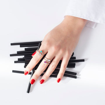 A hand with red nails adorned with multiple silver rings