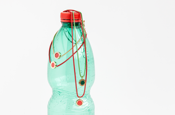 Red and green chain necklaces with circular red and green enamel pendants on a plastic water bottle