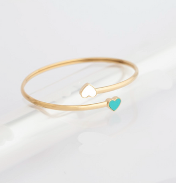 Minimalist gold cuff bracelet with a white and a turquoise heart charm