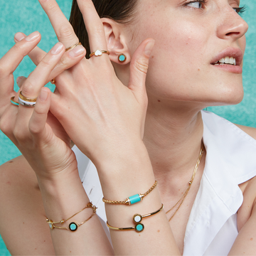 Woman wearing turquoise jewelry: ocean earrings, Amare & Wewa rings, and gold bracelets.