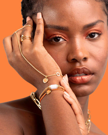 A close-up portrait of a Black woman wearing Jason Hyde orange chip jewelry