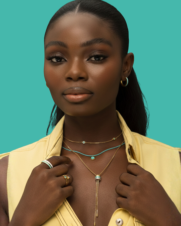 Close-up portrait of a woman wearing layered gold and turquoise jewelry