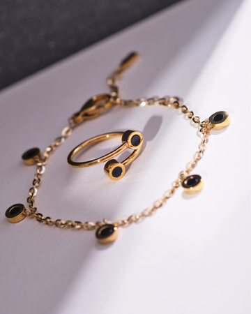 Gold chain bracelet with black circular charms and a matching open ring