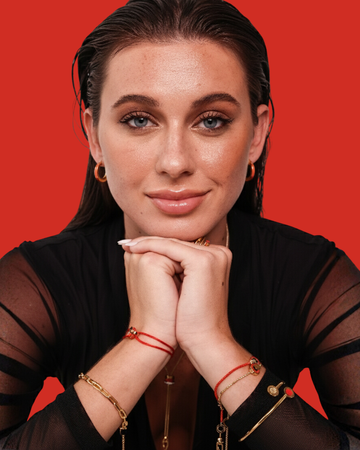 Close-up portrait of a woman wearing layered gold and red jewelry