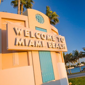 A large, retro-style "WELCOME TO MIAMI BEACH" sign 