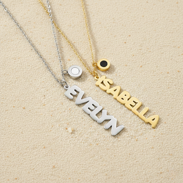 Personalized silver and gold name necklaces with charms on a sandy beach background.
