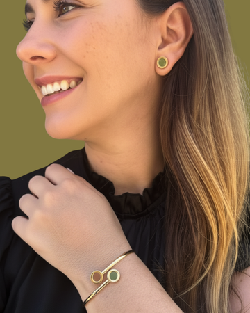 Smiling woman wearing a gold bangle bracelet and stud earrings 