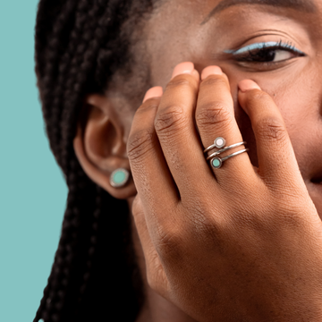 Close-up of a model wearing silver rings and earrings with turquoise and white chips