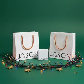 Christmas gift packaging set with two white JASON bags, small box, and colorful holiday lights.
