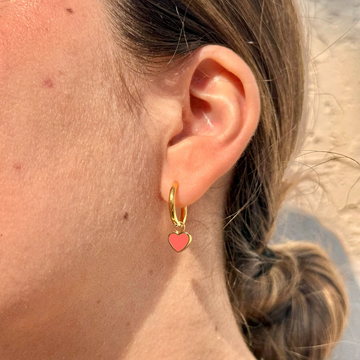 Woman wearing Jason Hyde gold hoop earrings with coral heart charms in a modern everyday look.