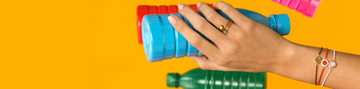 Female hand wearing Jason Hyde jewelry, holding a blue recycled plastic bottle 
