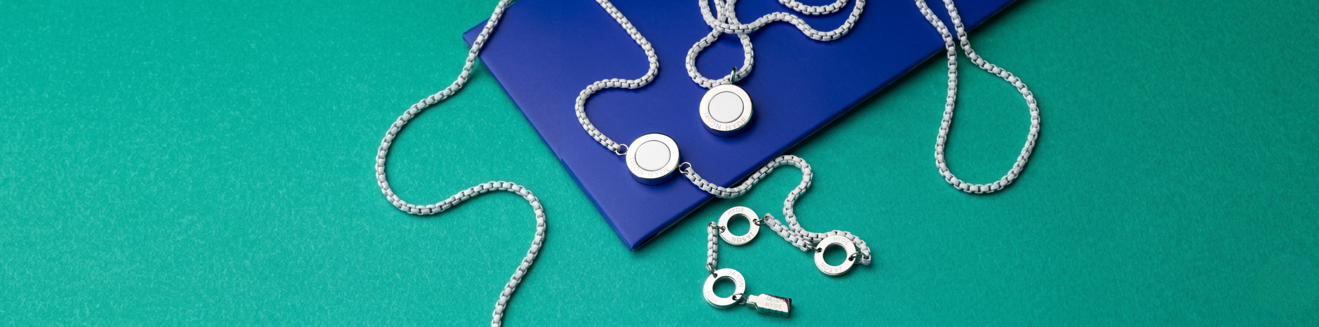 Two silver-colored chain necklaces with circular white pendants and a silver-colored chain bracelet