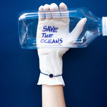 woman holding plastic bottle with "save the oceans" sign wearing sustainable bracelet