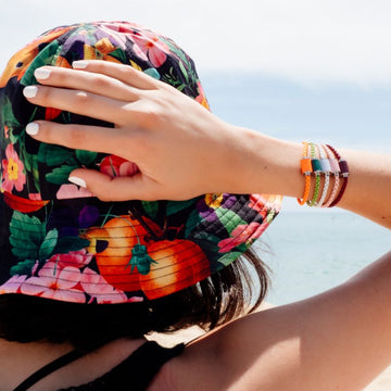 Thalassa magnet bracelets in orange, green, white, pink and plum in woman's wrist wearing hat