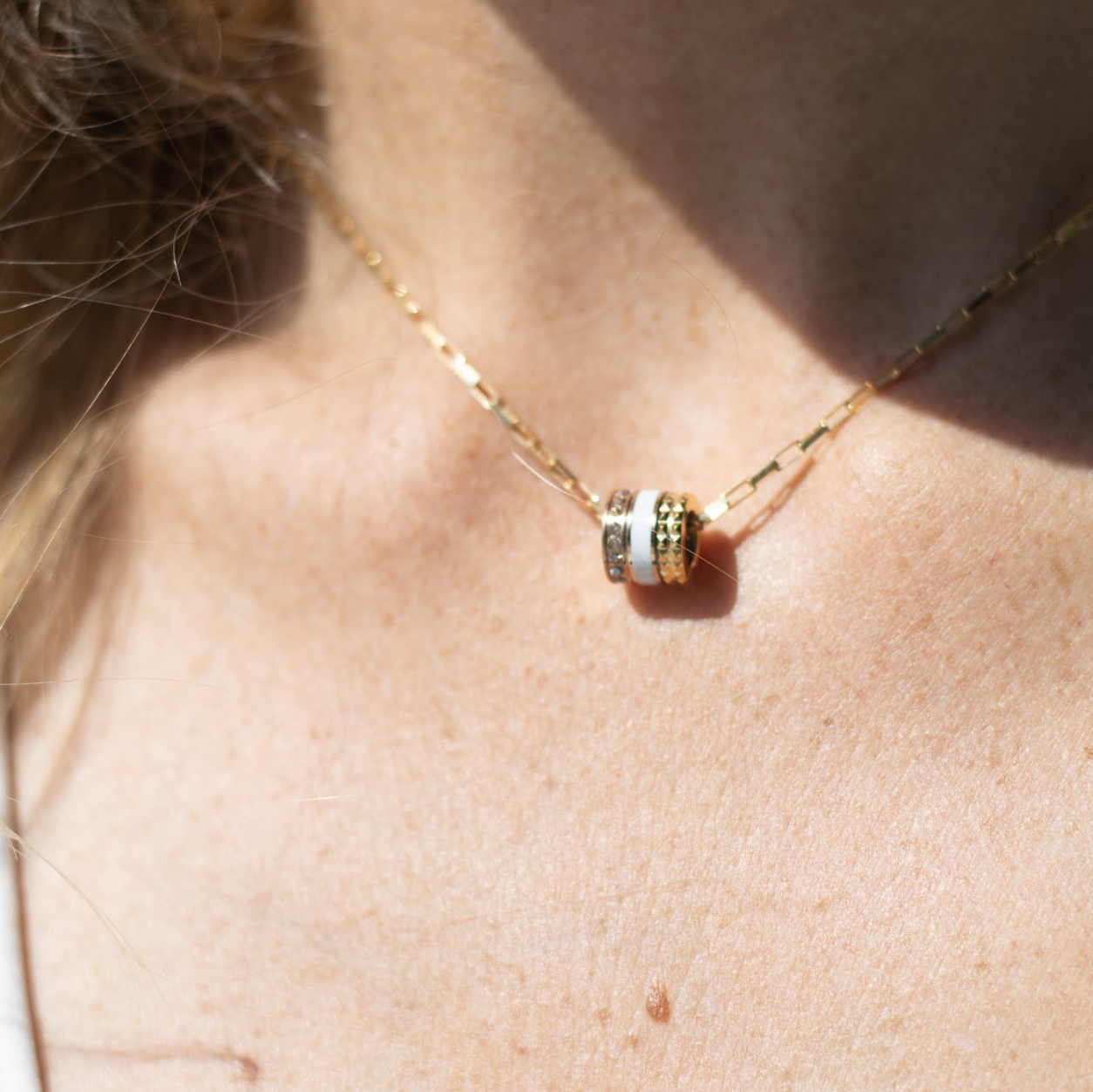 Jason Hyde gold necklace with white and gold cylindrical pendant.