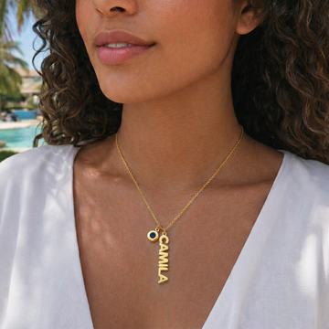 Woman wearing Jason Hyde gold custom nameplate necklace spelling "Camila" with a small charm.