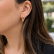 Close-up of a woman wearing a gold interlocking double ring earring