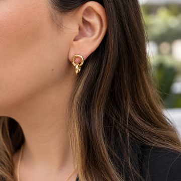 Close-up of a woman wearing a gold interlocking double ring earring