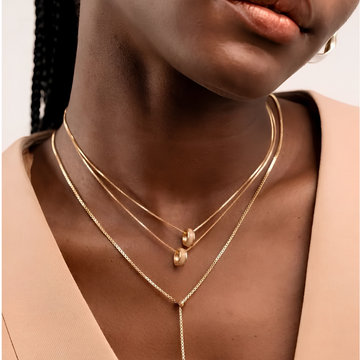 Layered gold snake and link chains with beige enamel circle charms