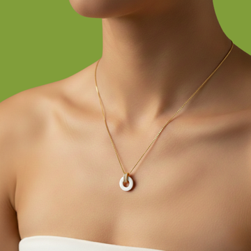Close-up of a gold chain necklace with a small white circular pendant