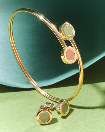 A open bangle bracelet featuring circular green and nutshell ends, paired with matching green stud earrings 