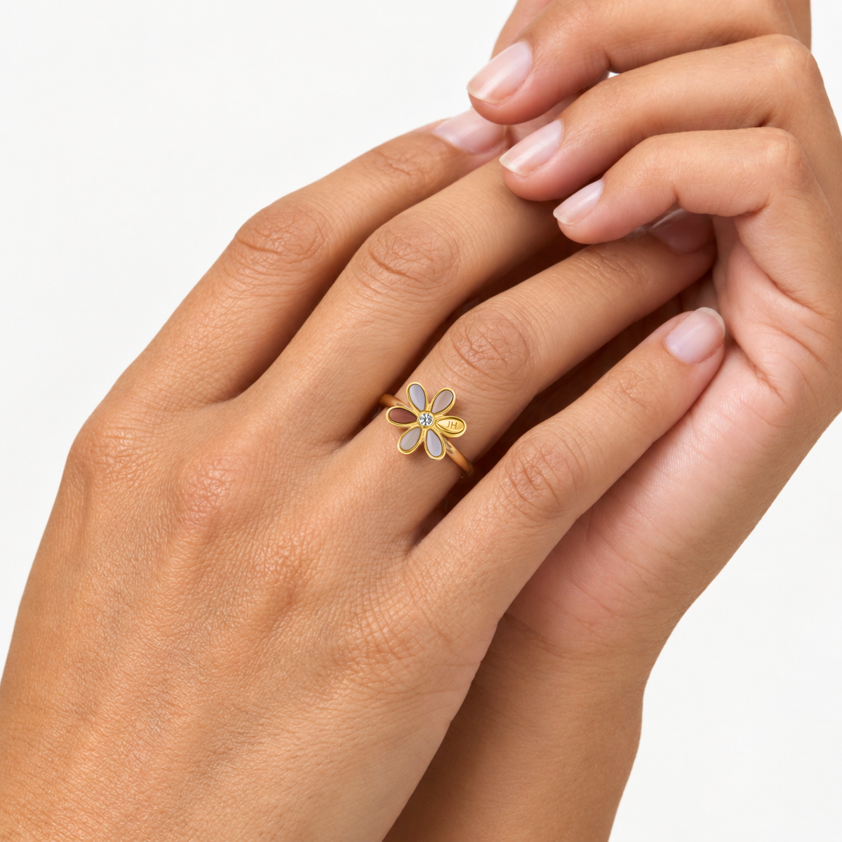 Gold flower ring with yellow petals and white detailing, worn on finger